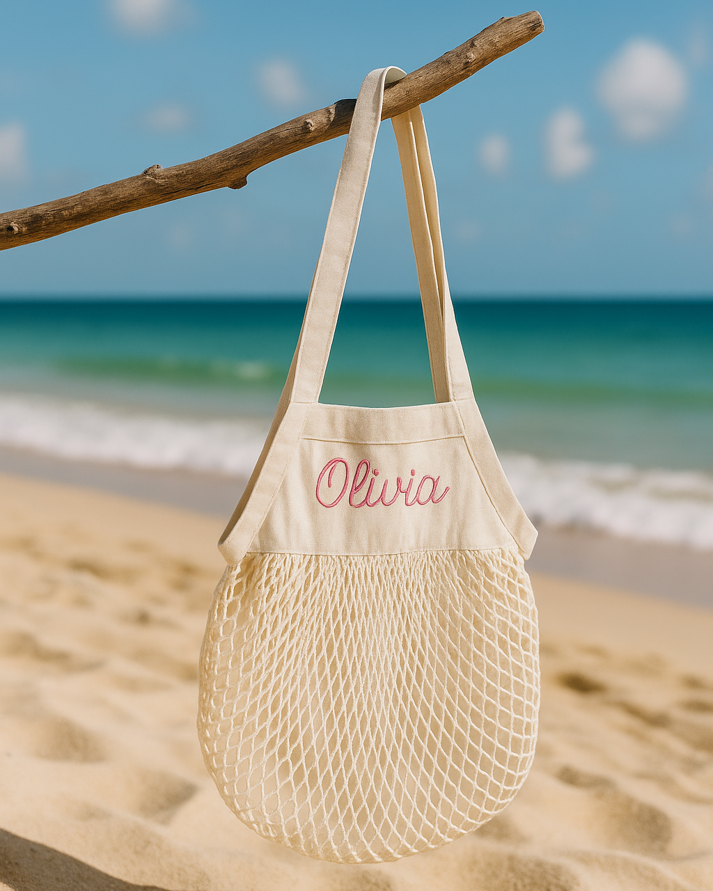 Beige mesh bag with personalised name embroidery on a beach with ocean in the background